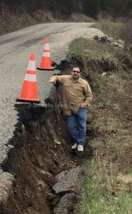 Clifford Hampton demonstrates the extent of a slip on Big Cabin Creek Road. Emergency funding has been applied for to make repairs. - Photo by Amy Hampton
