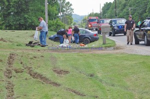 Officials help to clean up at the scene of a single vehicle accident on Memorial Day. Only minor injuries were reported. - Photo by Dennis Brown