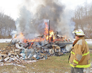 Garrison firefighter Hammer Cooper looks over the scene of a mobile home fire Monday morning on Mills Branch Road. No injuries were reported. The mobile home and all its contents were destroyed in the fire. - Dennis Brown Photo