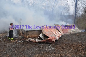 A firefighter sprays water on a fire that destroyed a cabin off Little Trace Road near Garrison. - Dennis Brown Photo