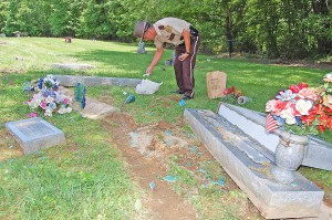 Deputy Bryon Walker collects evidence in Waring Cemetery at Garrison. Extensive damage was discovered Friday morning to indicate the vehicle involved is a 1997-2001 Honda CRV. - Dennis Brown Photo